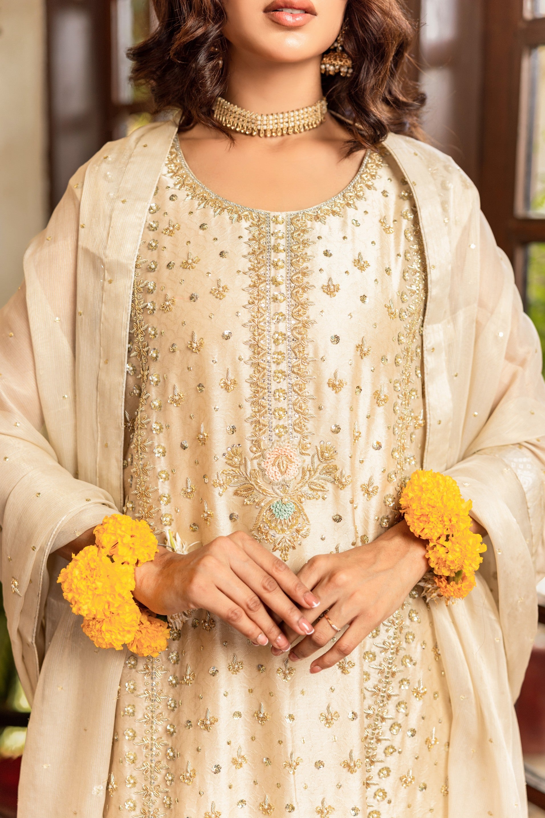 Woman in traditional formal shirt outfit with floral decorations, wearing a necklace.