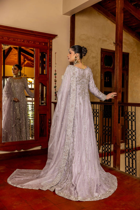 Woman in a silver embroidered gown standing in a room with wooden decor.