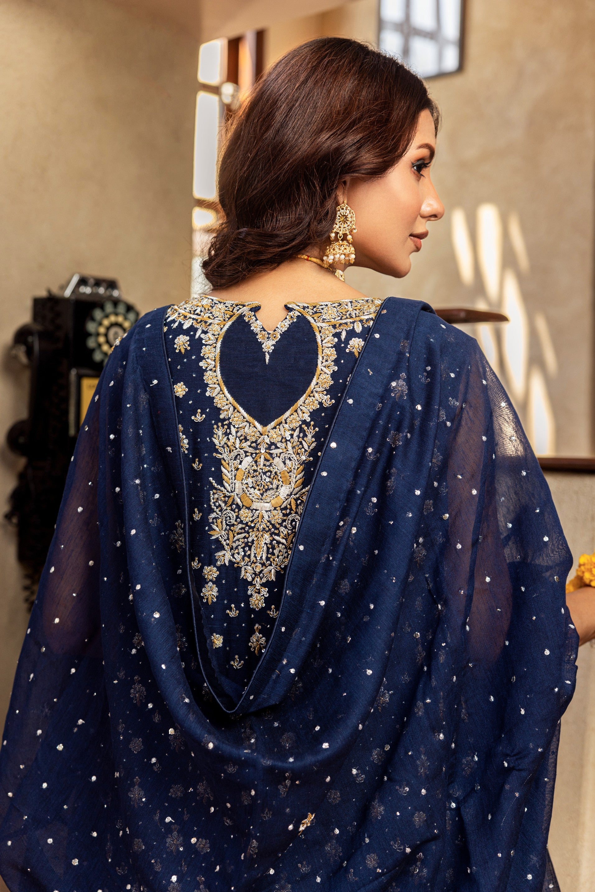 Woman wearing a navy blue embroidered formal shirt with a blurred indoor background