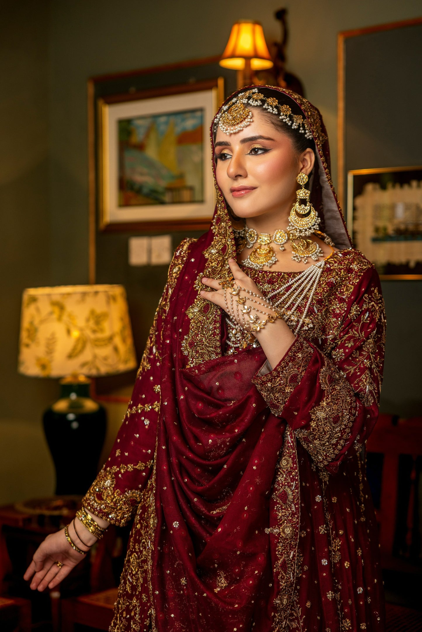 Woman in bridal sharara with jewelry in a room setting