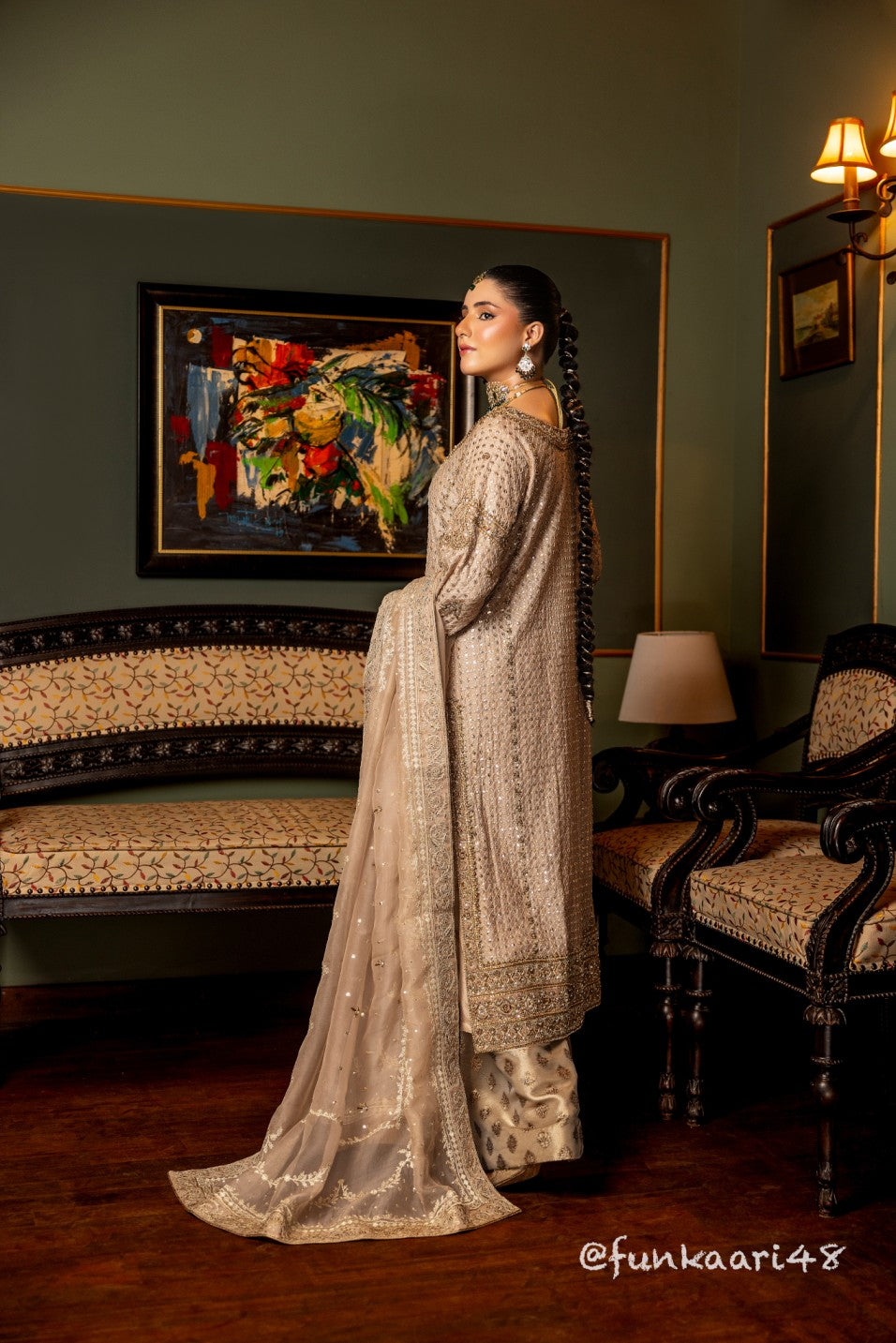Woman in a traditional wedding formal shirt standing in an elegant room with a painting and furniture.