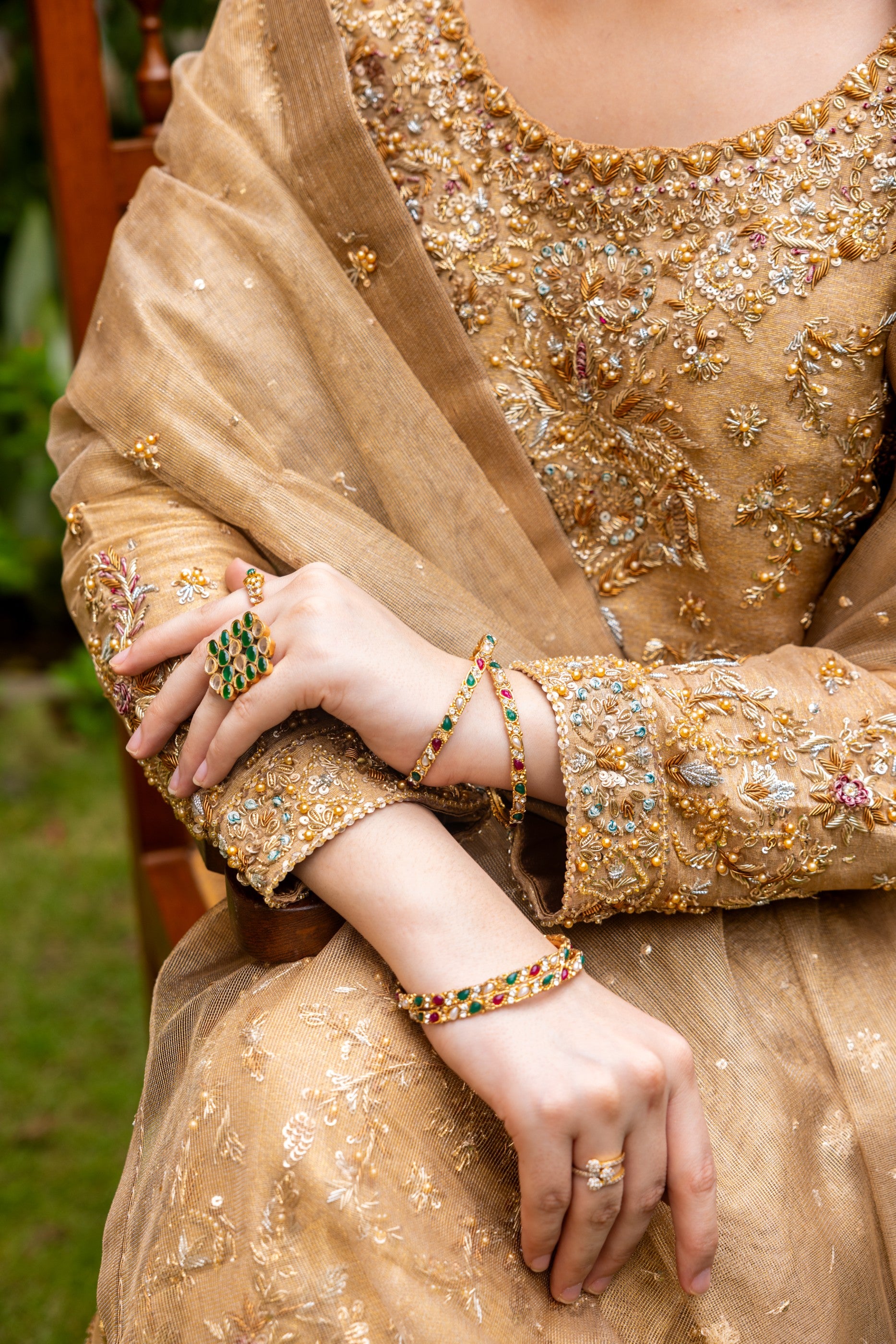 Close-up of a person wearing a gold embroidered party wear shirt with jewelry.