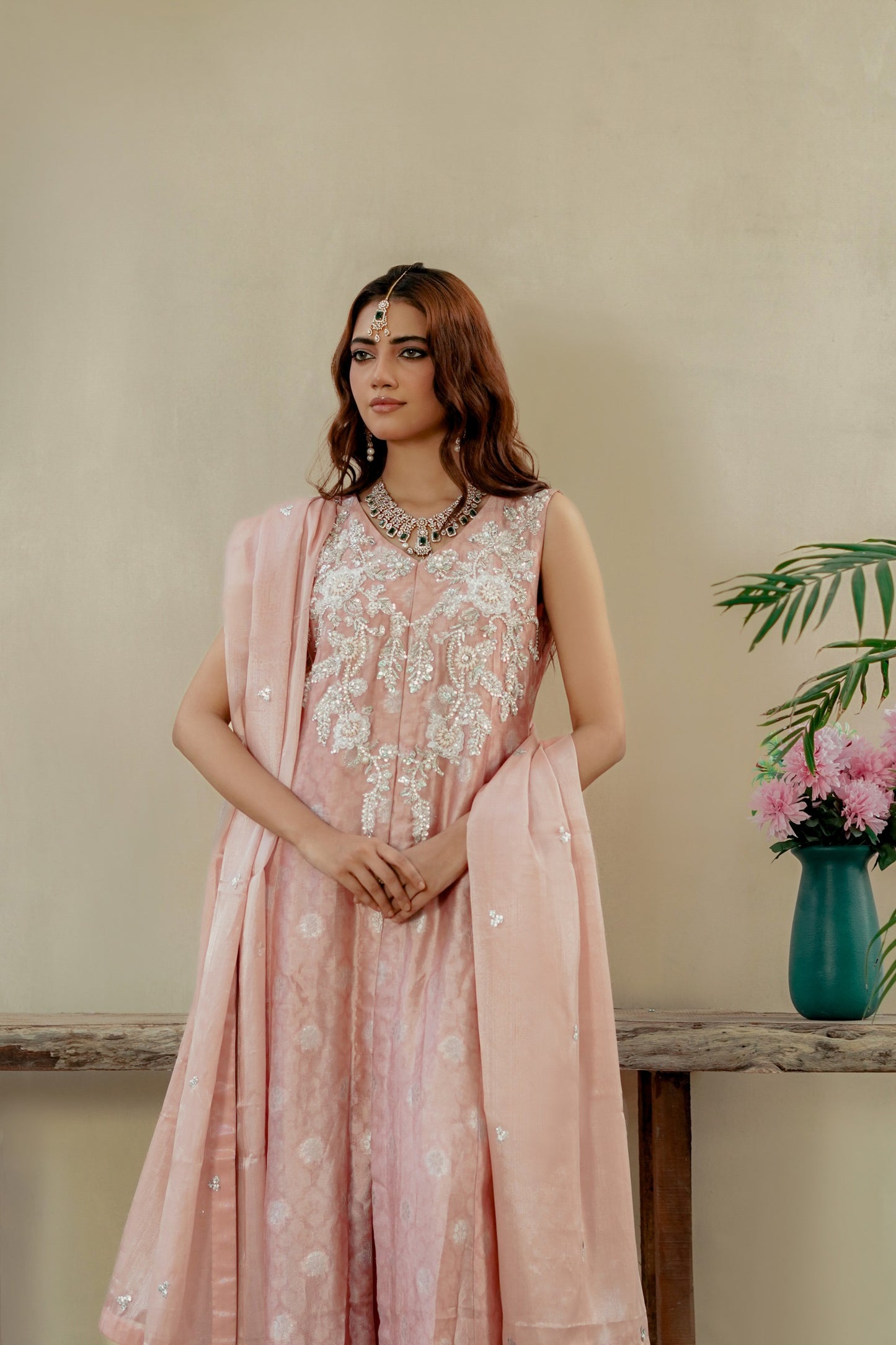 Woman wearing a pink floral formal maxi outfit with a plain background