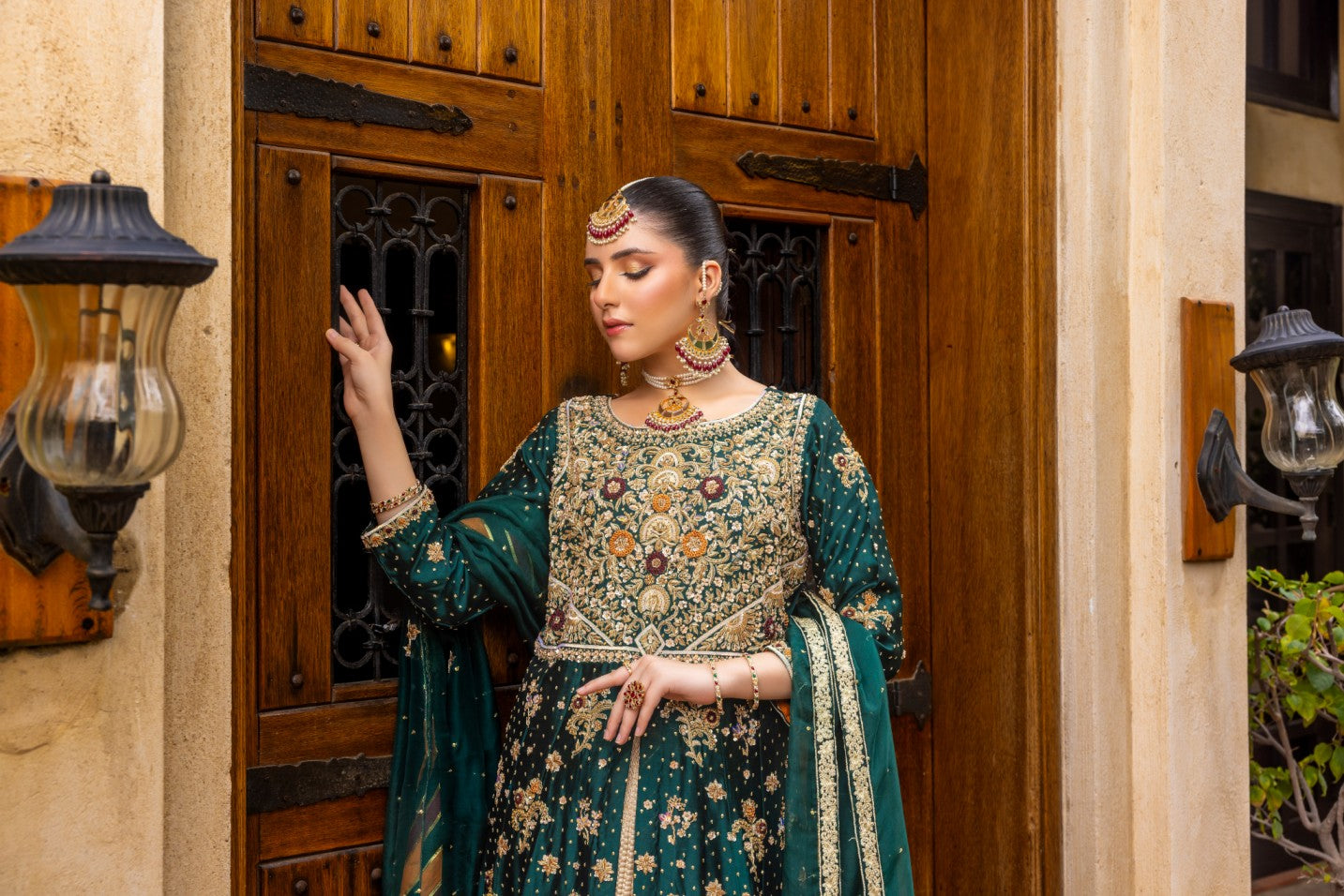 Woman in traditional front-open maxi dress standing in front of a wooden door.