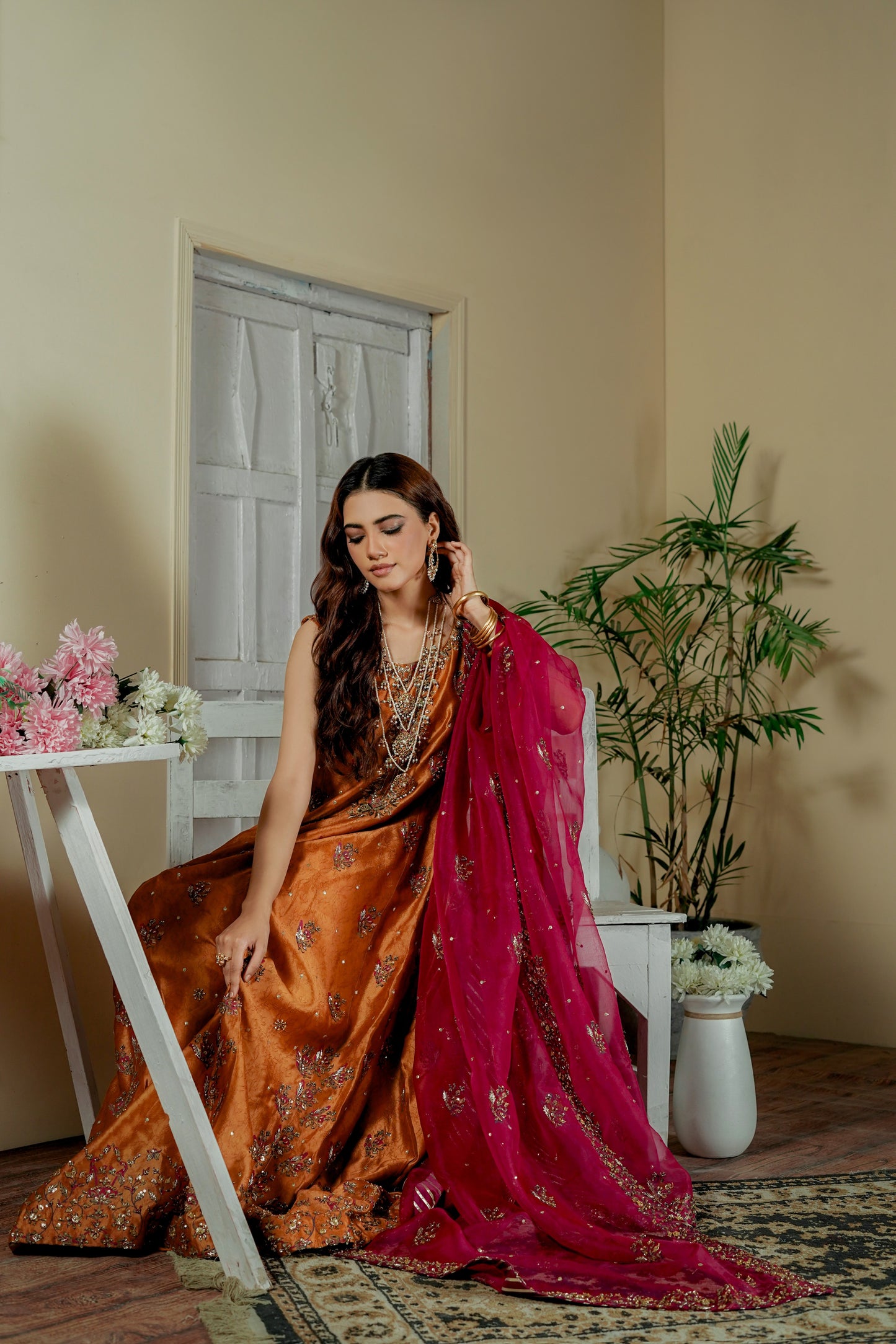 Woman in a traditional formal wear maxi sitting indoors with decor elements.