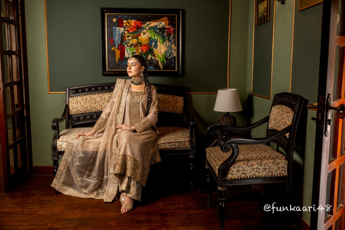 Woman in traditional wedding formal shirt attire sitting on a patterned chair in a decorated room.