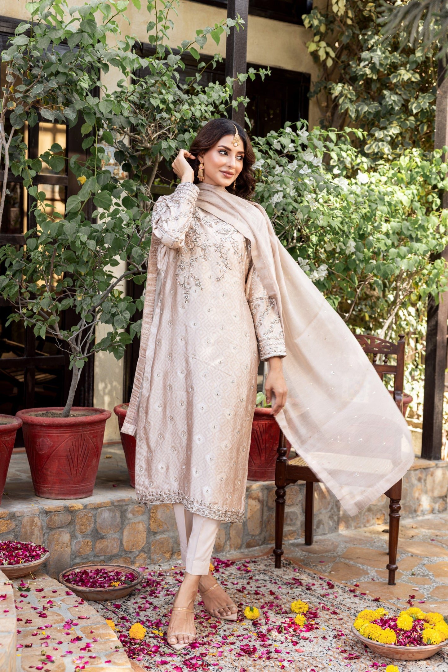 Woman in traditional formal basic shirt outfit standing outdoors with greenery and flowers around