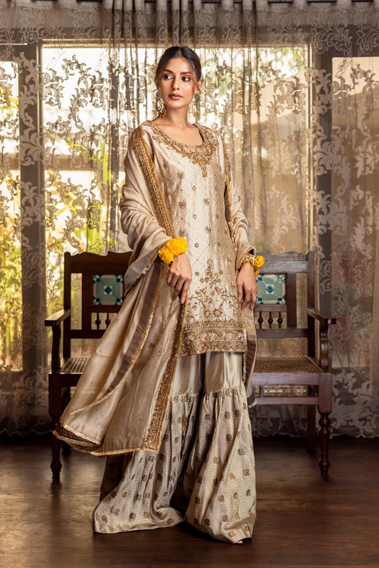 Woman in traditional Party Wear Garara standing in a decorated room with floral decorations.