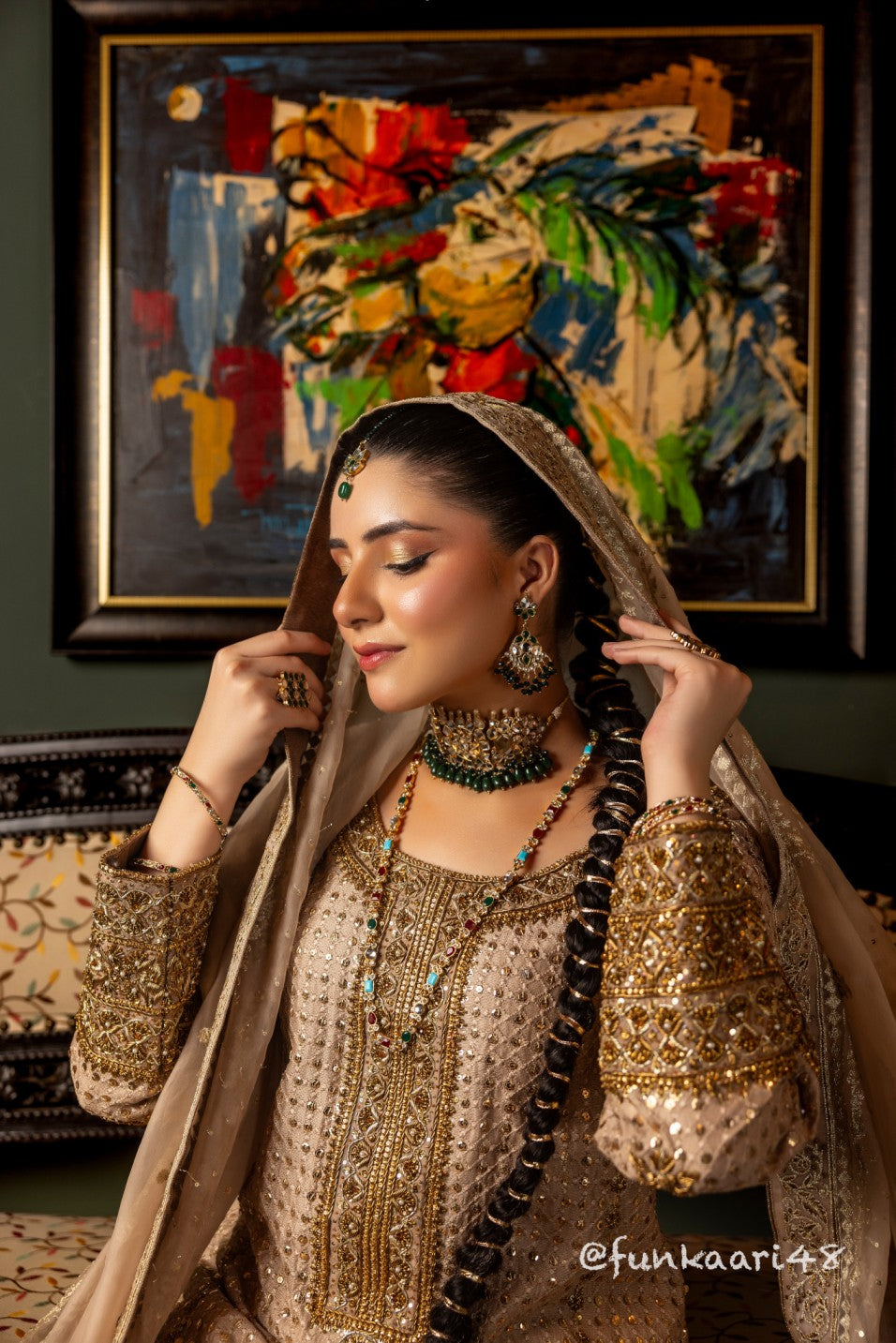 Woman in traditional wedding formal shirt attire with jewelry in a room with a colorful abstract painting.