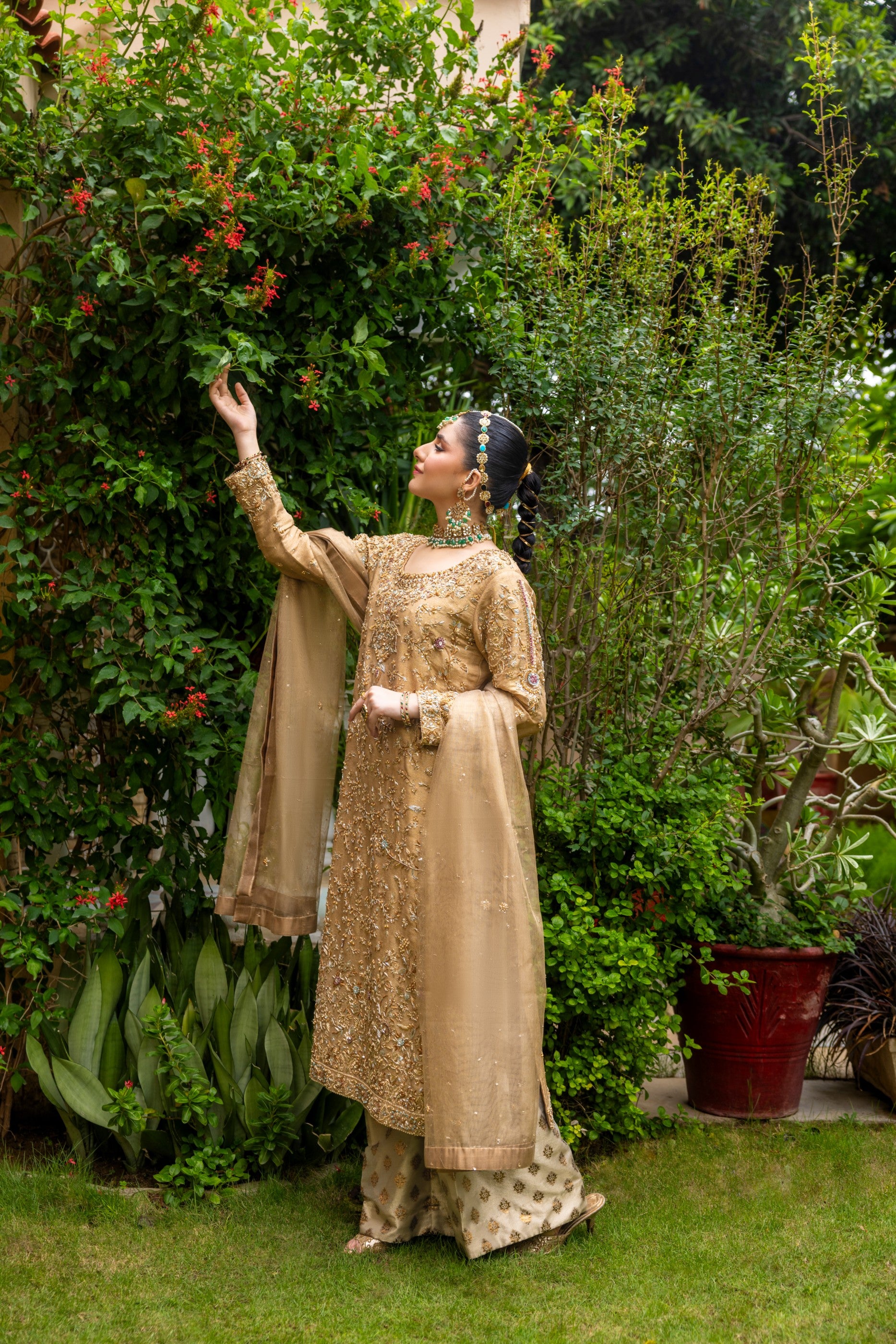 Woman in traditional embroidered party wear shirt with jewelry in a garden setting