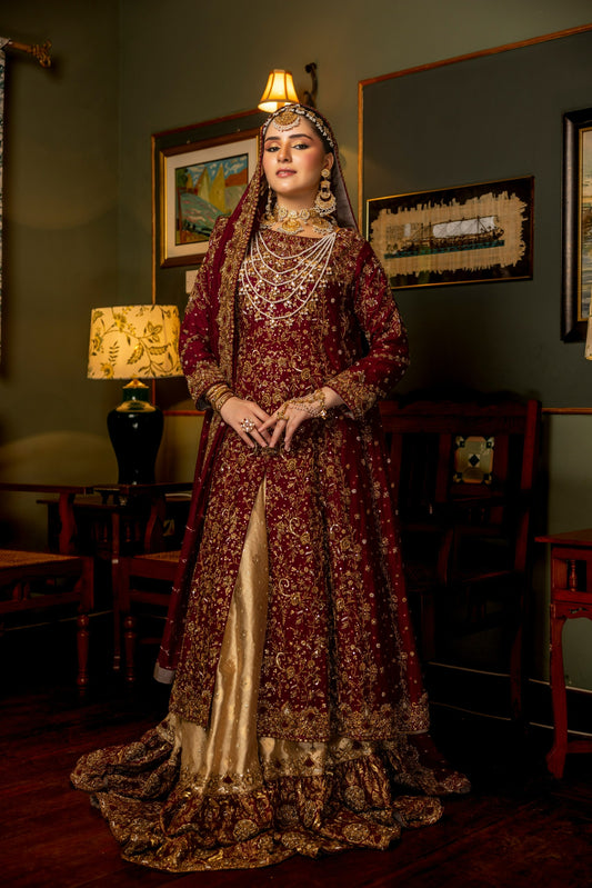 Woman in a traditional maroon and gold dress standing in a room with decor elements.