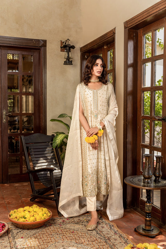 Woman in a traditional formal shirt outfit standing in a room with decorative elements.