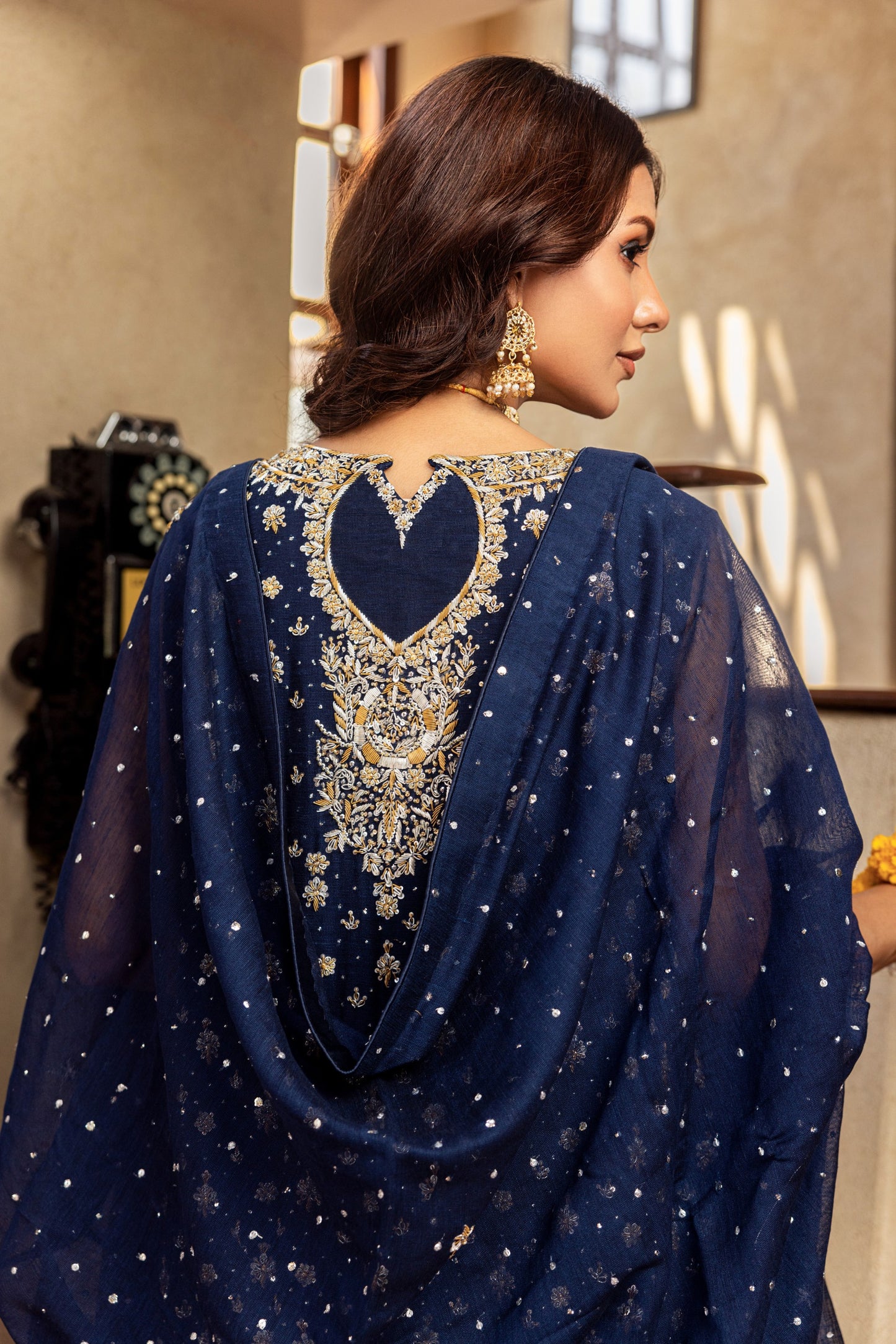 Woman wearing a navy blue embroidered formal shirt with a blurred indoor background