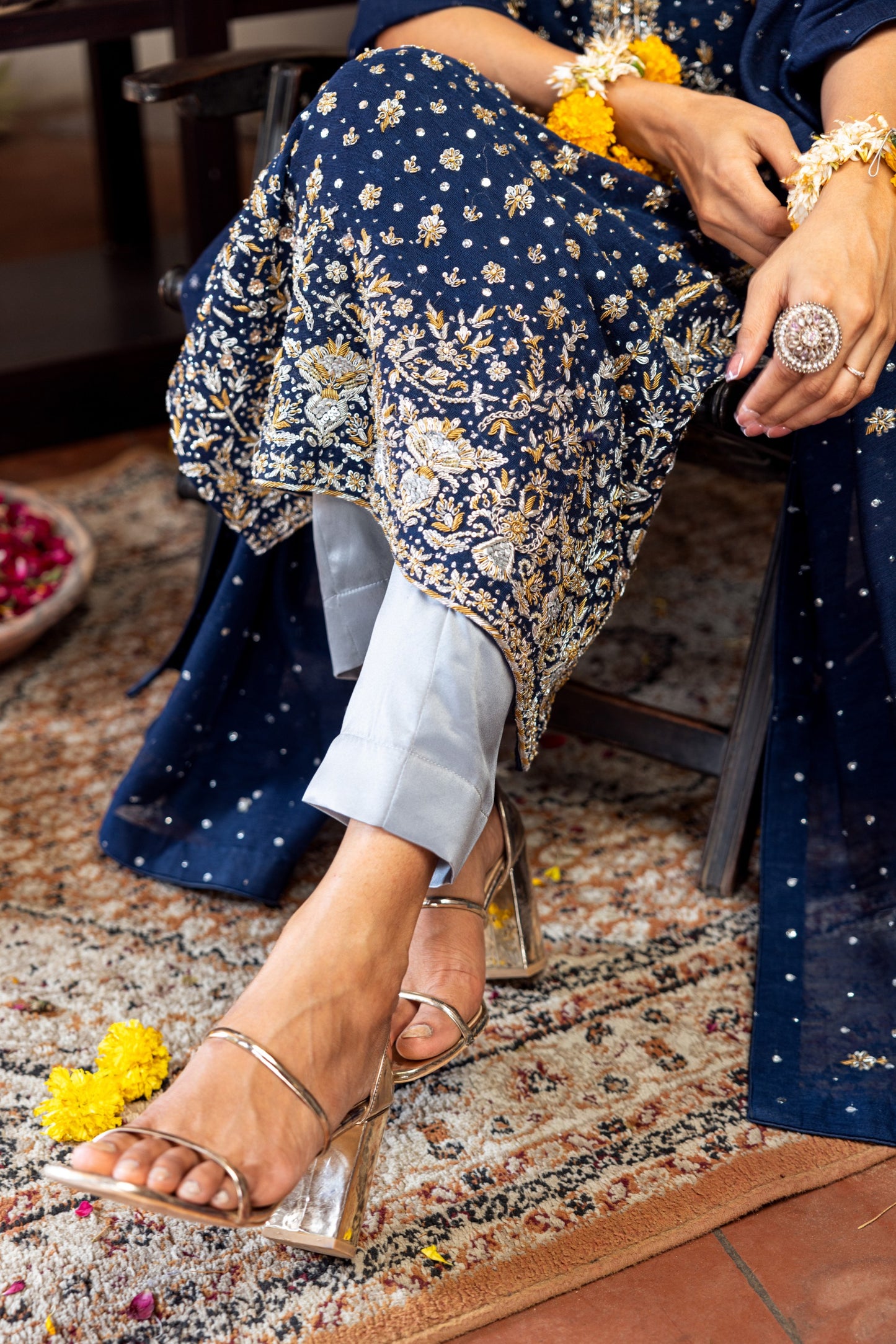 Person wearing a navy floral dress with gold accents, sitting on a patterned rug.