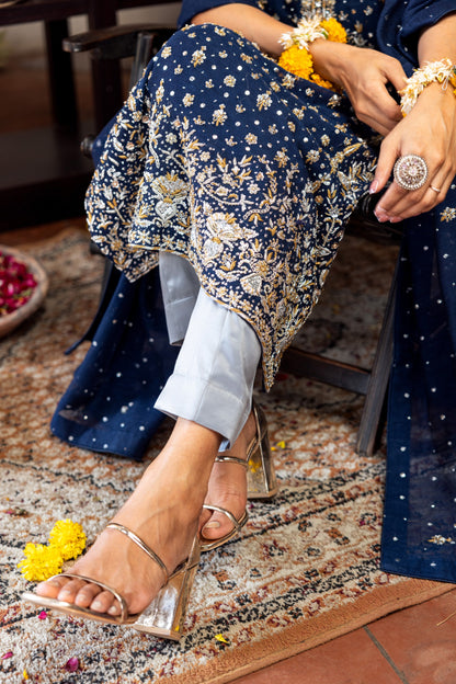 Person wearing a navy floral dress with gold accents, sitting on a patterned rug.