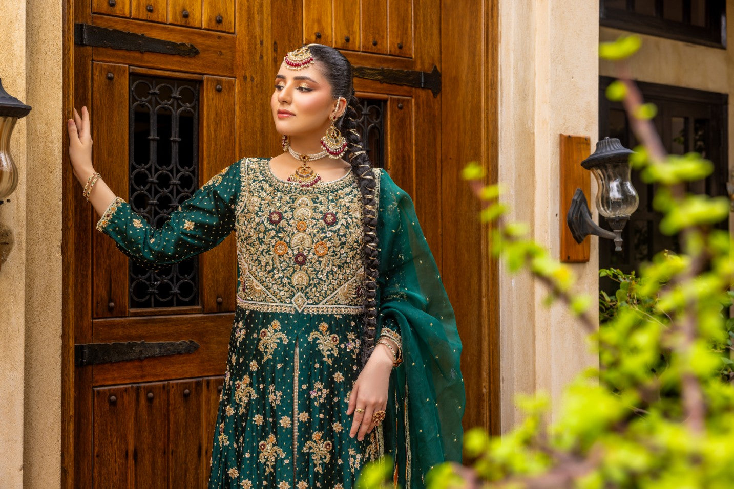Woman in traditional front-open maxi outfit standing in front of a wooden door.